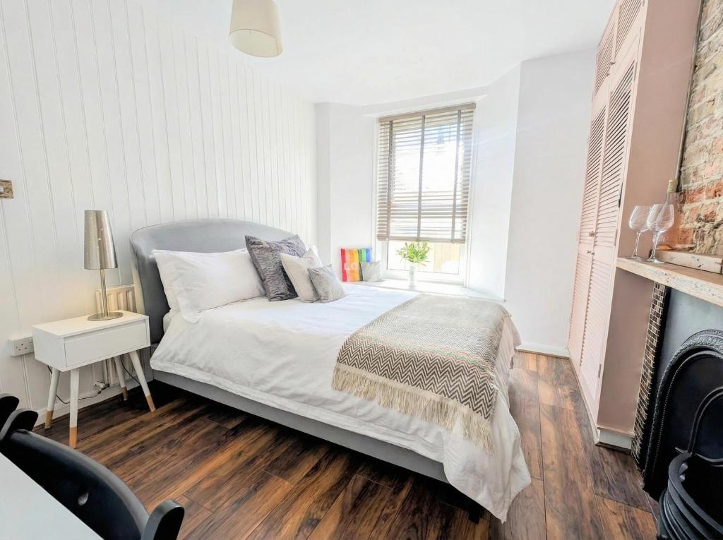 a white bedroom with a bed and a fireplace at Sunny Homestay Room, 10 Mins North Laine, 6 Mins Station in Brighton & Hove