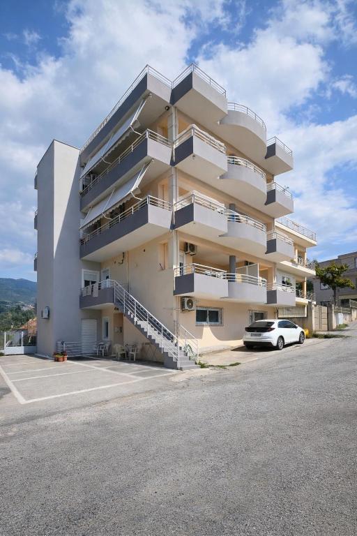 a white apartment building with a car parked in front at Studios Theodore in Kalamata