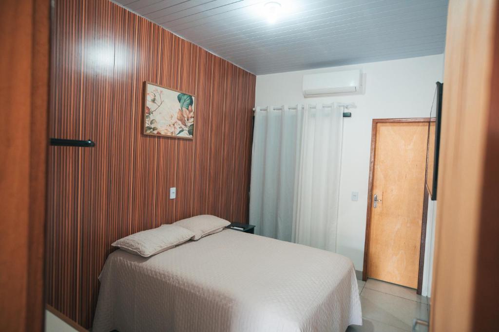 a bedroom with a bed and a wooden wall at Residencial Antônio Floriza in Sinop