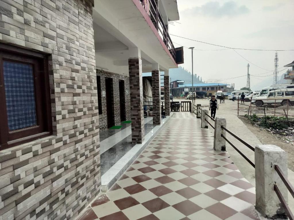 a brick building with a checkered floor on a sidewalk at Hotel Shri Yamuna Gaulok Dham in Kharsālī