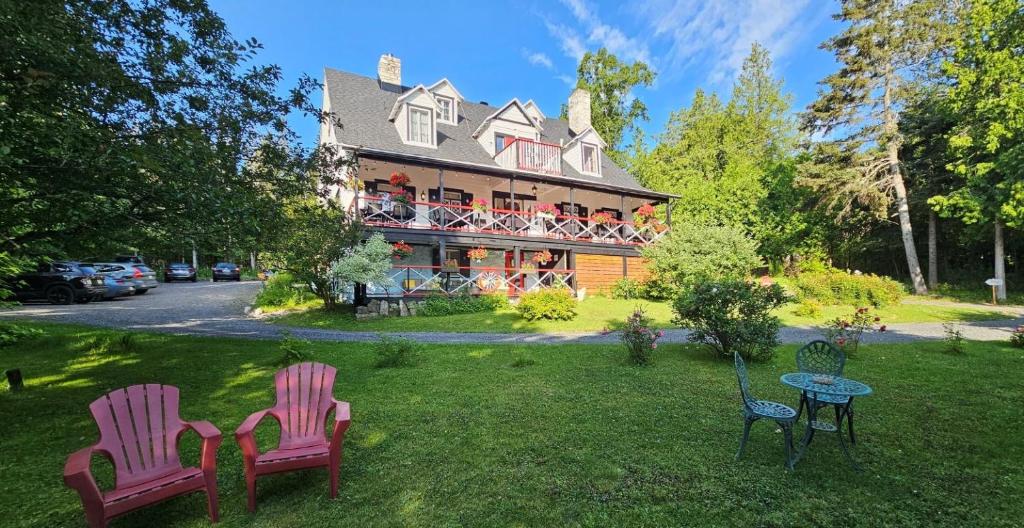 two chairs and a table in front of a house at Auberge La Châtelaine in La Malbaie