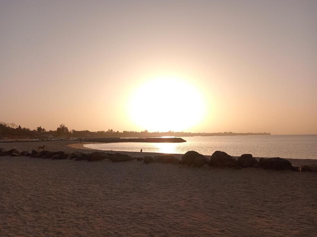 a sunset on a beach with the sun setting at Appartement Keur Diam Saly in Saly Portudal