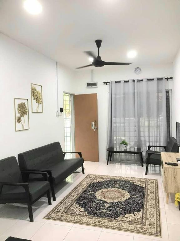 a living room with a black couch and a rug at Abadi Homestay Ipoh in Ipoh