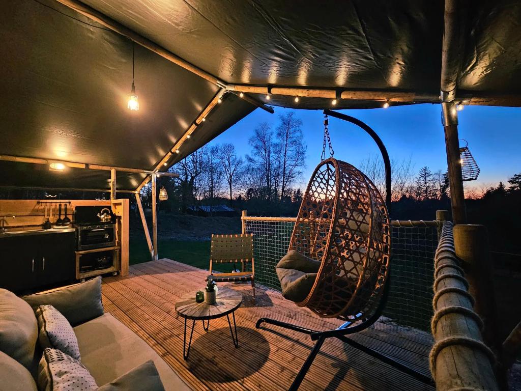 a porch with a swing and a hammock at Le Ranch Camping et Glamping in Madranges