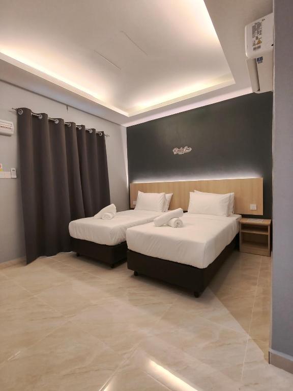 two beds in a hotel room with two beds sidx sidx sidx at Rimba Inn in Kijal