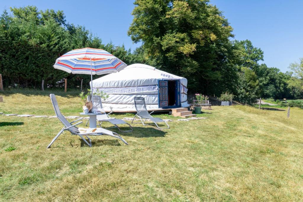 a woman sitting in a chair under an umbrella next to a rv at Yourte mongole insolite en pleine nature in Pouilly-sous-Charlieu