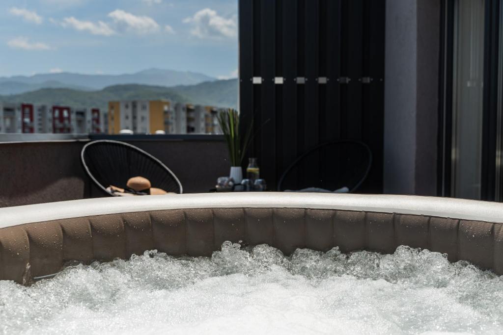 a bath tub filled with water in a balcony at Skylark - Singapore Penthouse with Jacuzzi & Panoramic View in Braşov