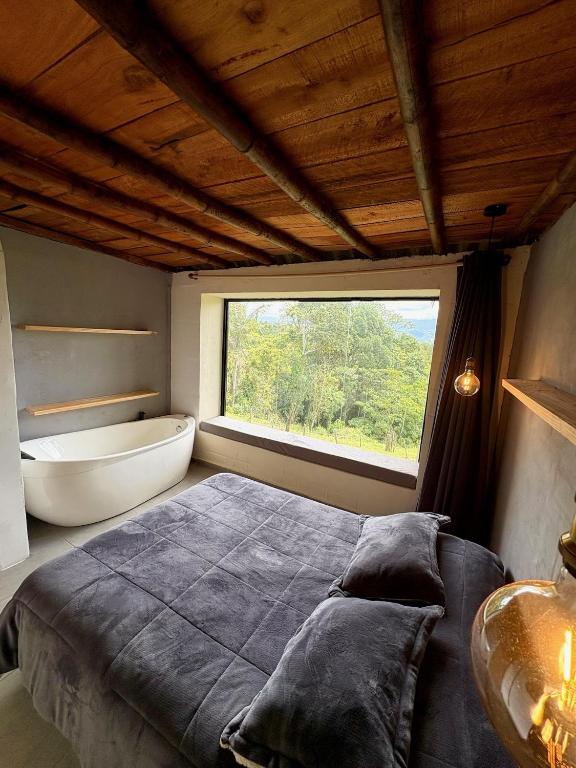 a bedroom with a bed and a tub and a window at La Morada Quindio cabaña campestre in Boquía