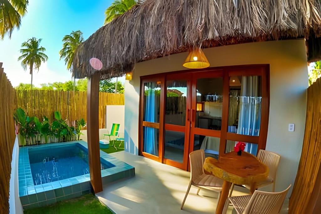 a villa with a pool and a table and chairs at Maysu Patacho Chalé Piscina Privativa in Pôrto de Pedras