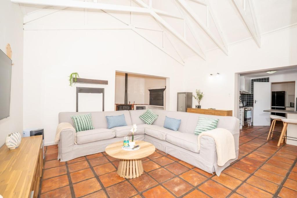 a living room with a white couch and a table at Benguela Cottage in Langebaan