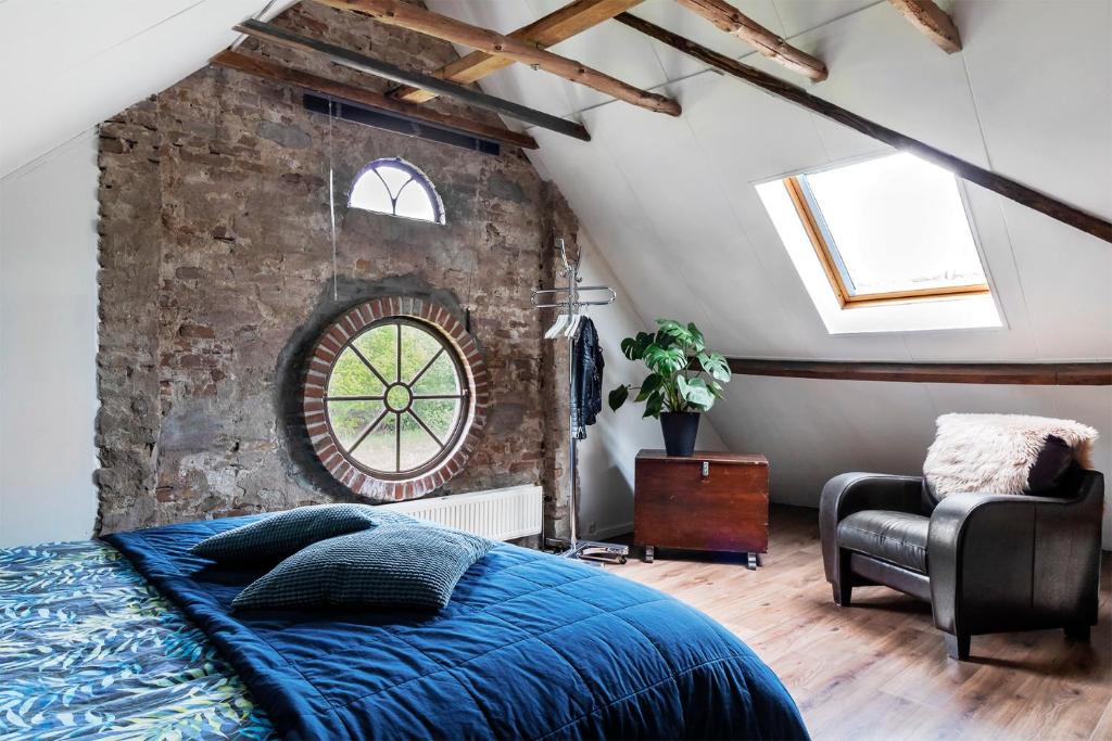 a bedroom with a brick wall and a bed and a chair at Bed and Breakfast Lovenem - ruime studio met zwembad en sauna op de Veluwe in Leuvenheim