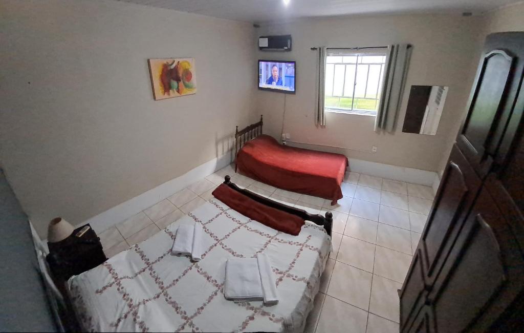 a room with a bed and a chair in it at Básico e funcional, com 2 ambientes, sem fogão, com garagem, zona nobre in Pelotas