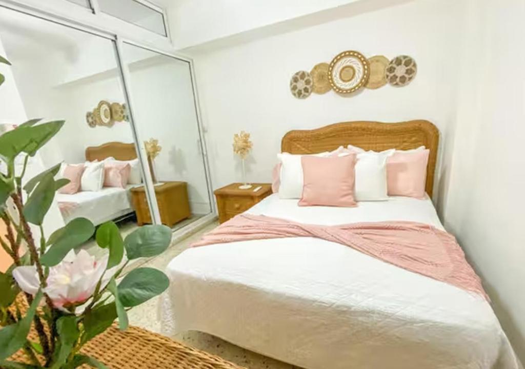 a bedroom with a bed with pink pillows and a mirror at Colonial Zone 2BR Apartment Prime Location in Santo Domingo