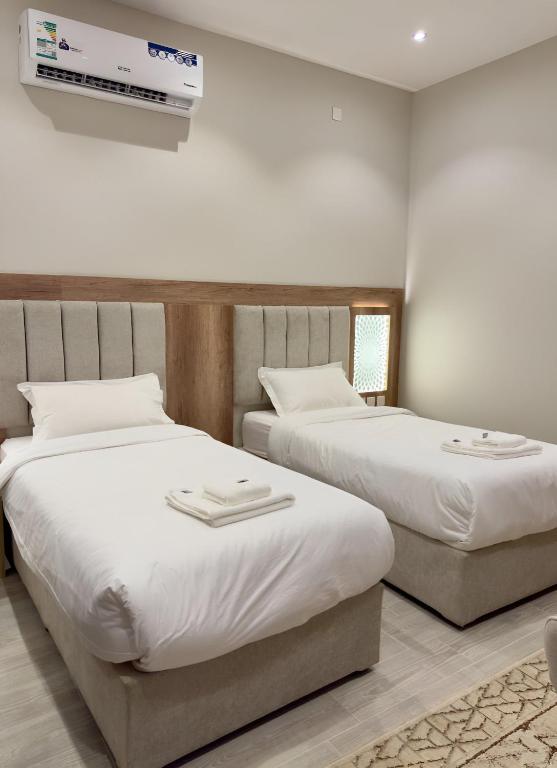 a bedroom with two beds and a tv on the wall at Alturya in Al-ʿUla