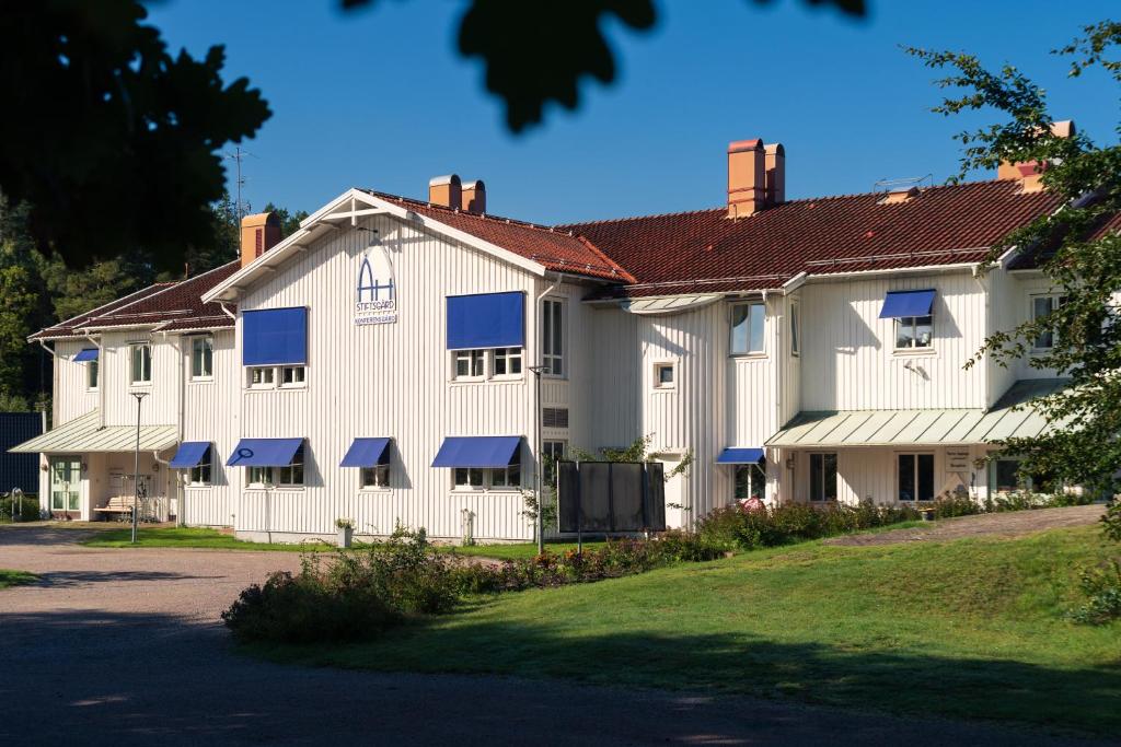 a large white building with blue windows and a yard at Åh Stifts- & Konferensgård in Ljungskile