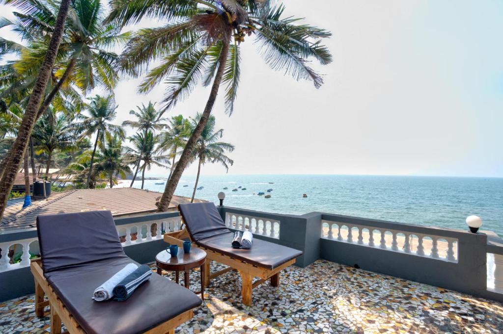 two chairs and a table on a balcony overlooking the ocean at Anjuna Beach House in Anjuna