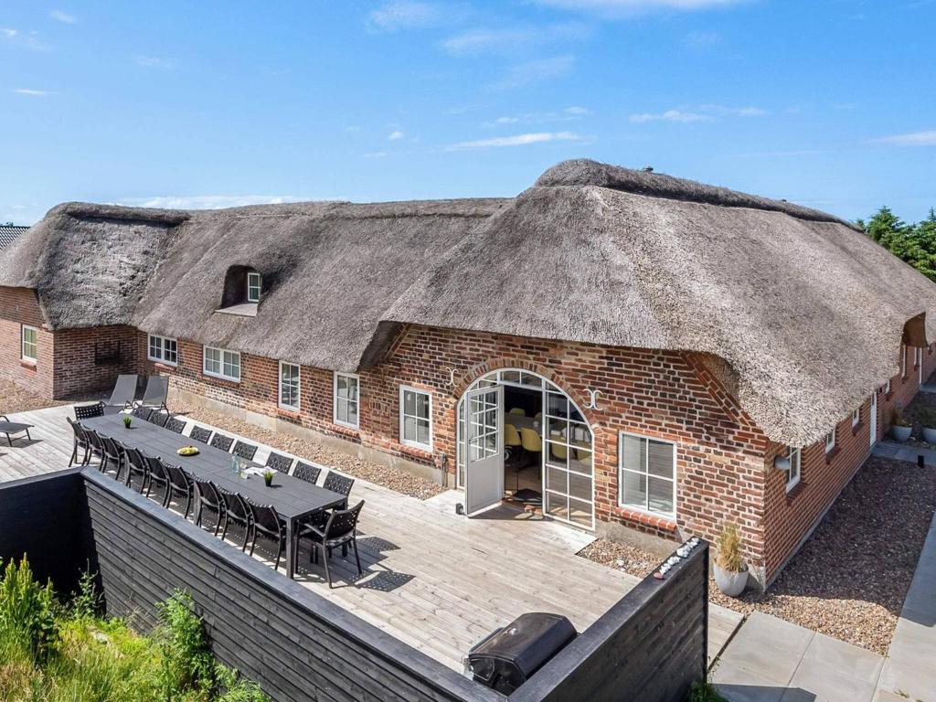 a large brick building with a thatched roof with a patio at 5 star holiday home in Ringkøbing in Ringkøbing