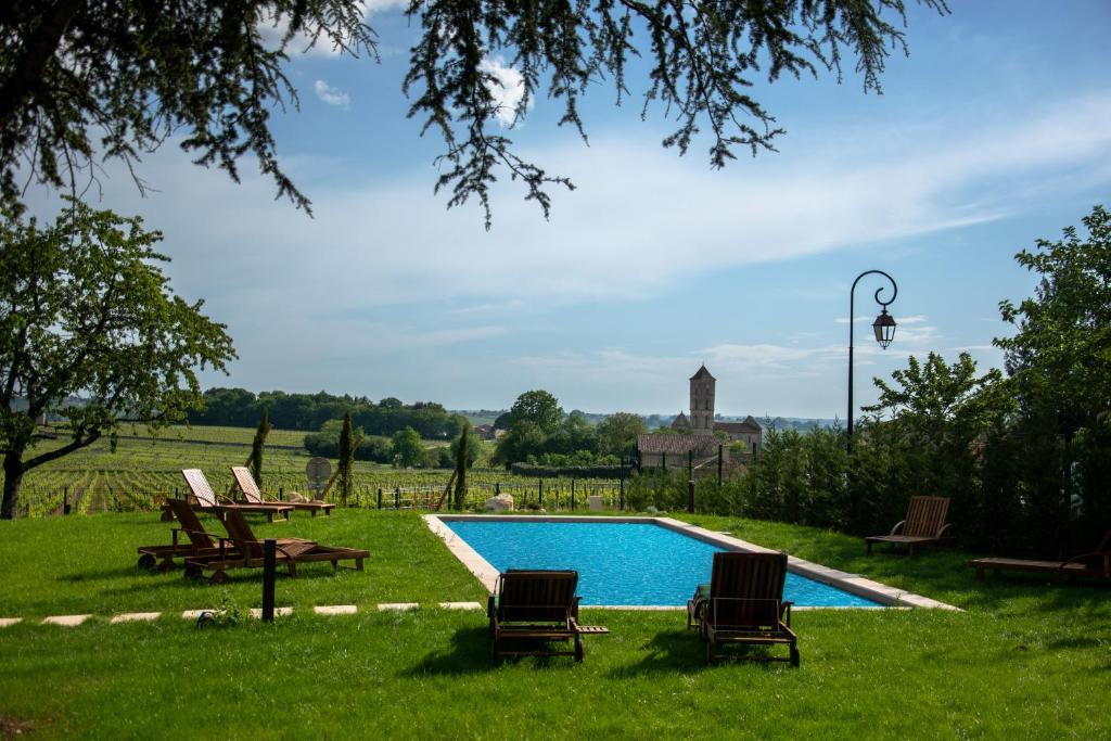 a swimming pool in the grass with two lawn chairs at Aux ducs de Sienne in Montagne