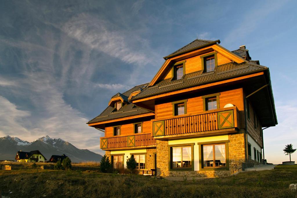 a large wooden house with a gambrel roof at Vila Mlynica in Veľká Lomnica