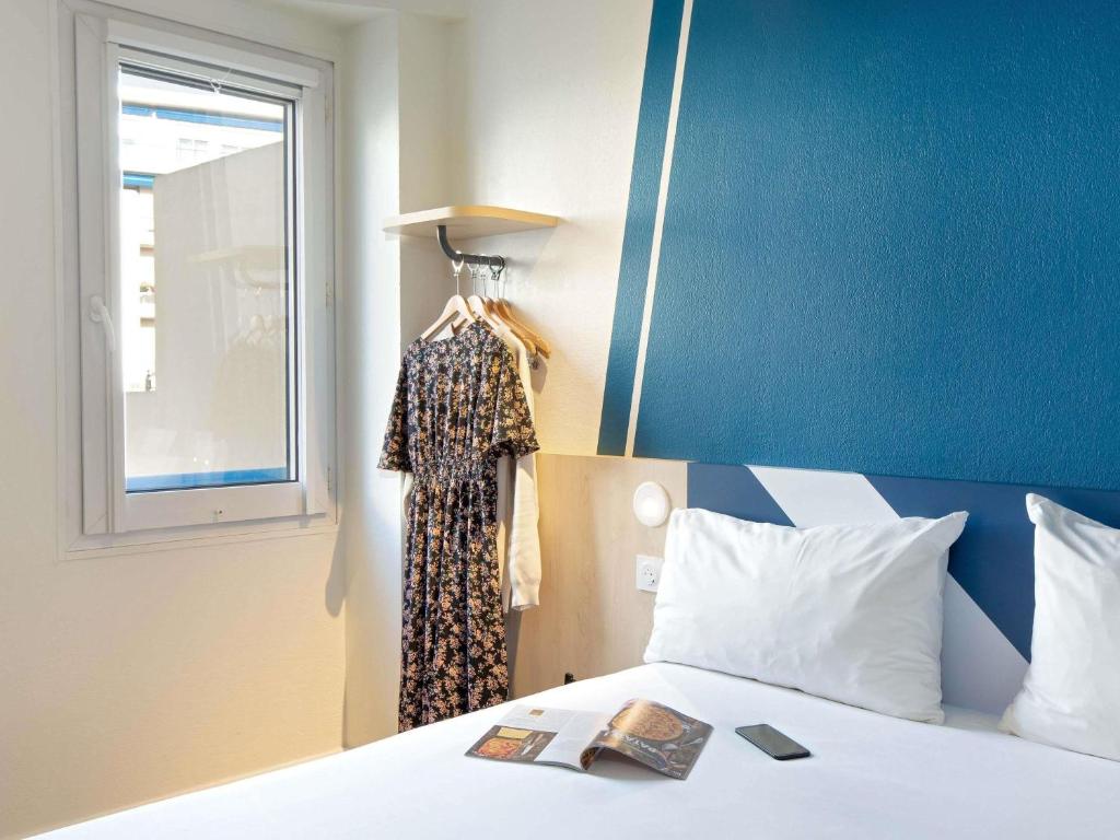 a bedroom with a bed and a dress hanging from a window at Ibis Budget Toulon Centre in Toulon