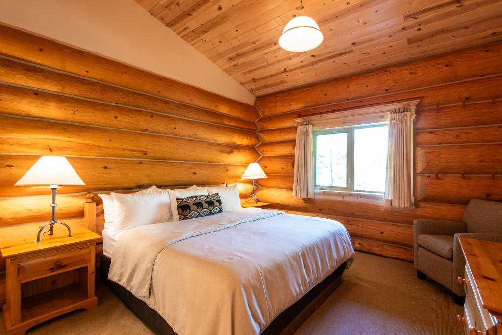 a bedroom with wooden walls and a bed with a window at Mike Wiegele Helicopter Skiing in Blue River