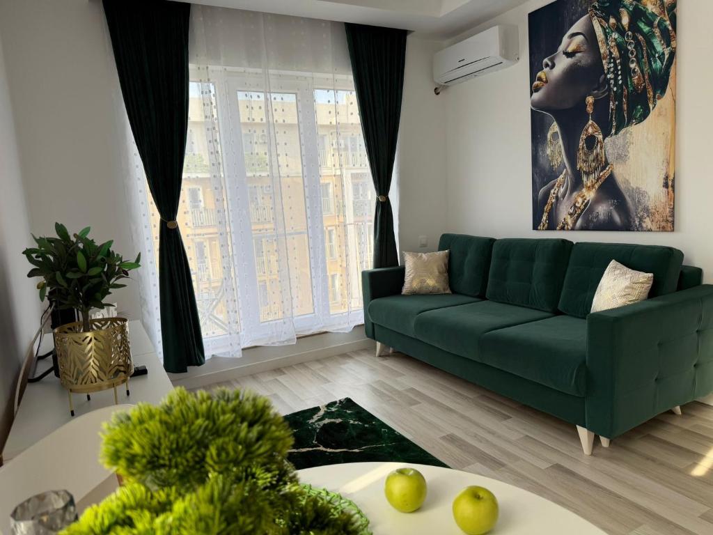 ein Wohnzimmer mit einer grünen Couch und einem Tisch in der Unterkunft SunSet Studio by Cosmopolis in Ştefăneştii de Sus
