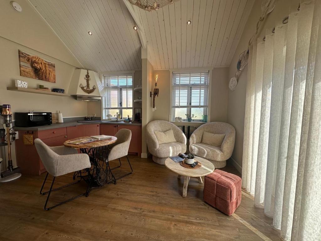 a living room with a table and chairs and a kitchen at Beach House Texel in De Koog