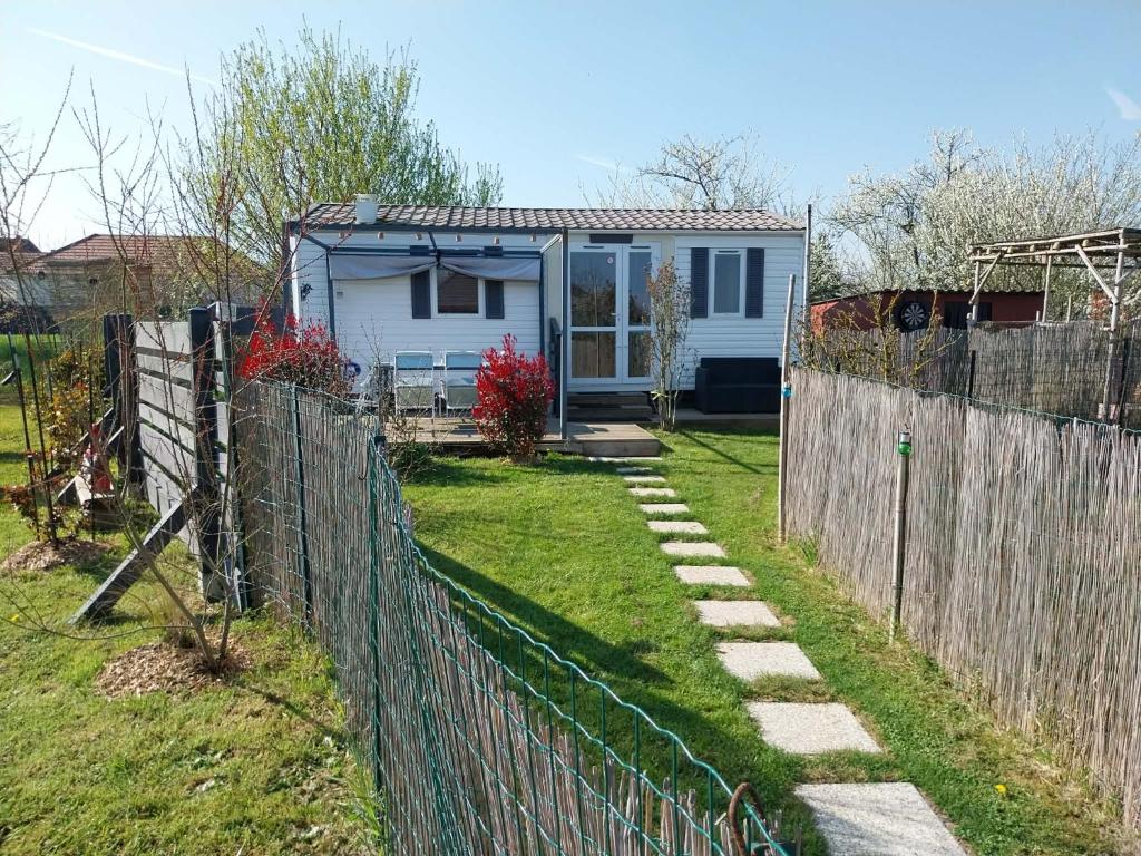 a fence in front of a small white house at Chez Elvis et Agnès, logement climatisé in Saint-Loup