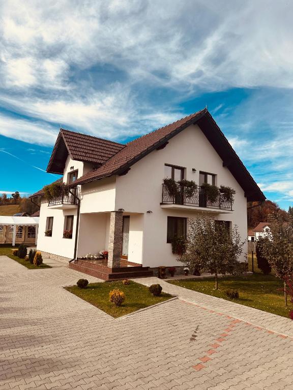 a white house with a brick driveway at Casa Tică in Vama Buzăului