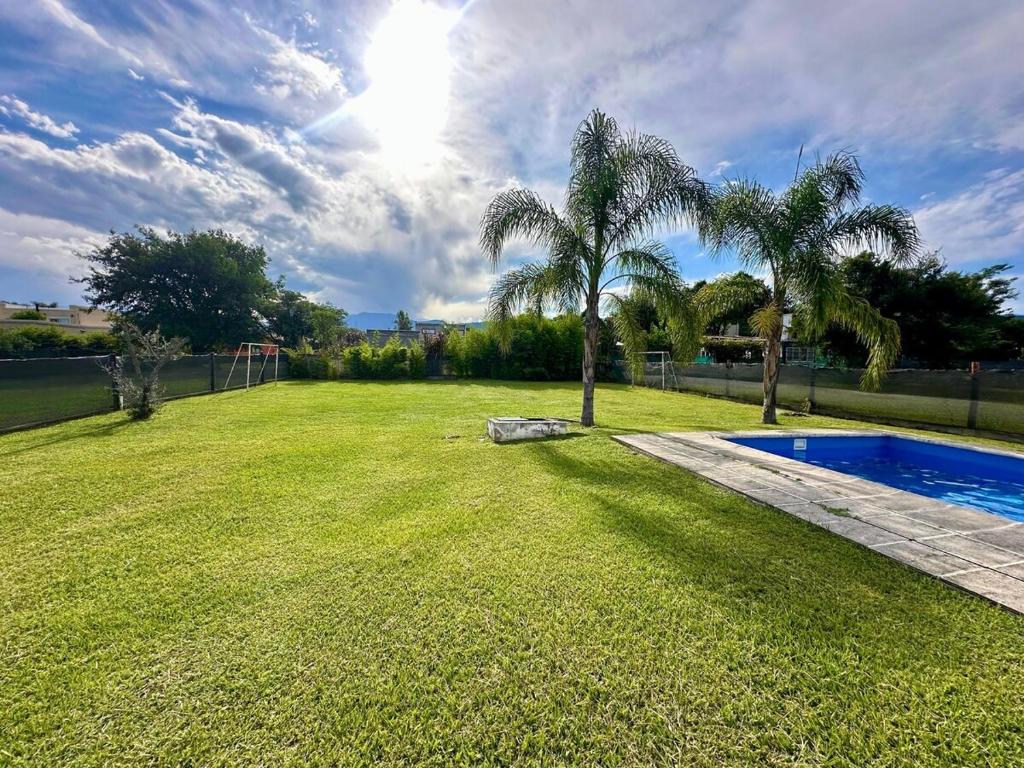a yard with palm trees and a swimming pool at Casa con pileta cerca de Salta in Salta