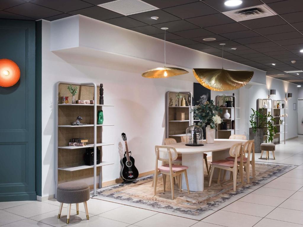 una sala da pranzo con un tavolo, sedie e una chitarra di ibis Caen Centre a Caen