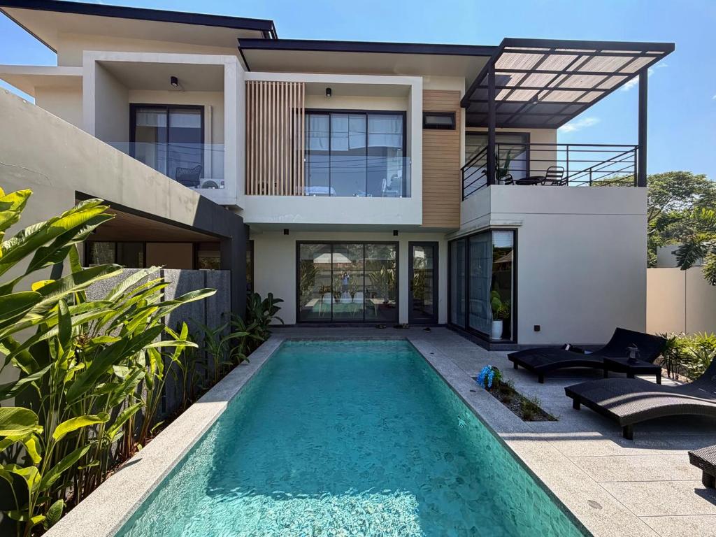 a villa with a swimming pool in front of a house at AURA STAY-Luxury Private Pool Villa walk to Kad Farang in Chiang Mai