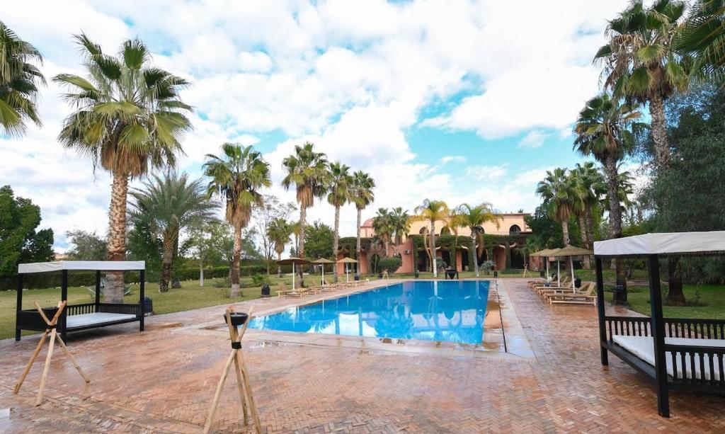 a swimming pool with palm trees in the background at Royal Moroccan House in Marrakesh