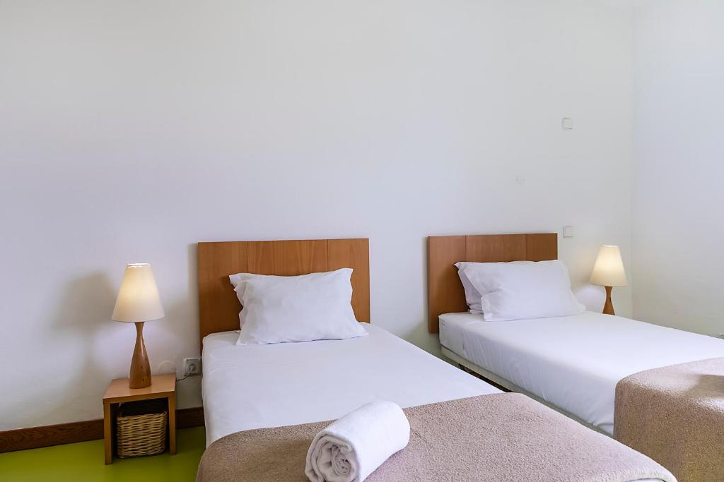 two beds in a hotel room with white sheets at HI Castelo Branco - Pousada de Juventude in Castelo Branco