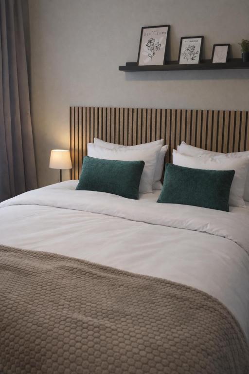 a large white bed with two green pillows at Hotell Marieberg in Kristinehamn