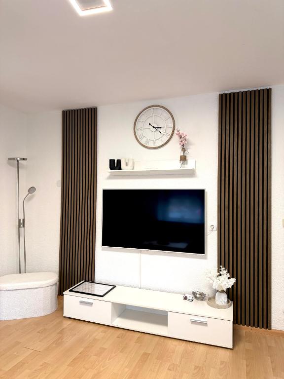 a living room with a television and a clock on the wall at Ferienwohnung LAZ am Dreiländereck in Bad Säckingen