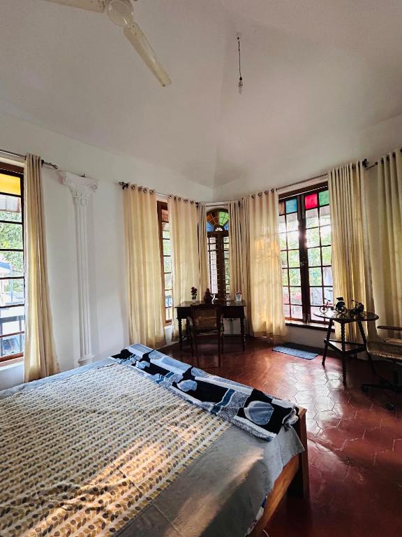 a bedroom with a large bed in a room with windows at Fort flora in Cochin