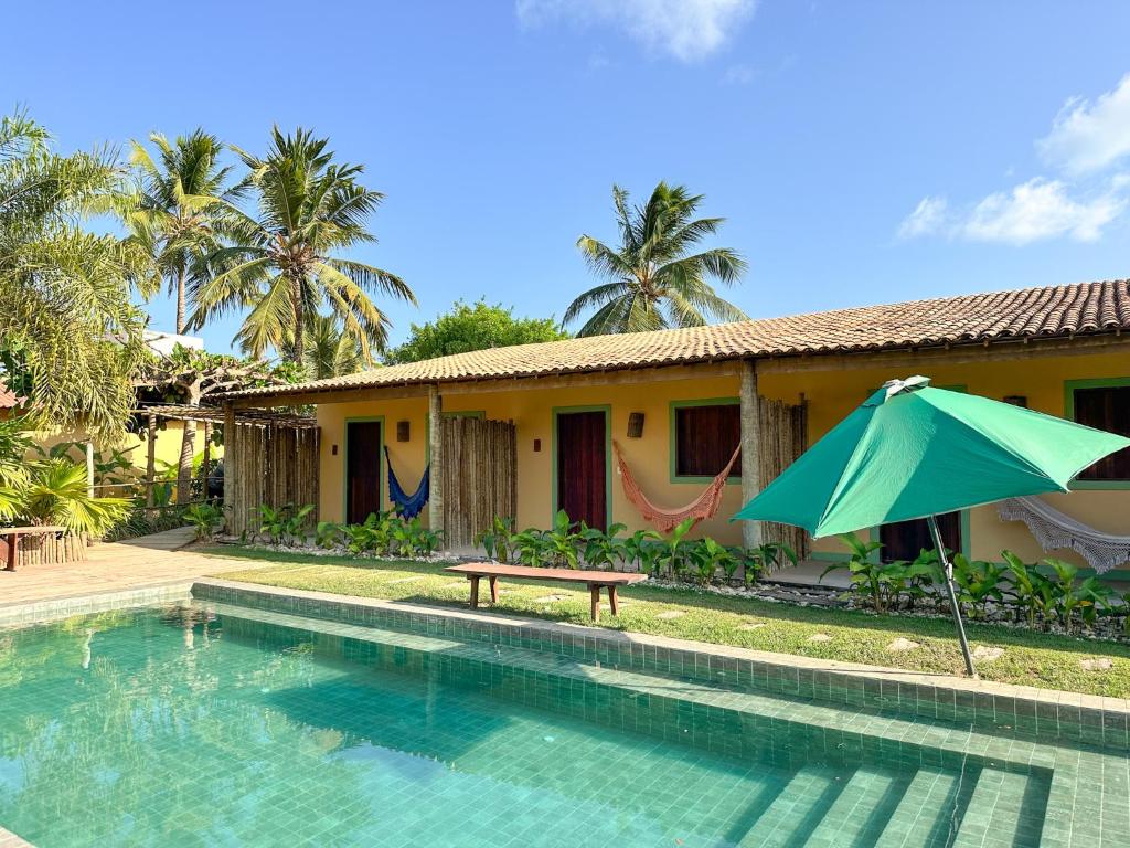 a house with a swimming pool and an umbrella at Pousada Rancho Luar in Pôrto de Pedras