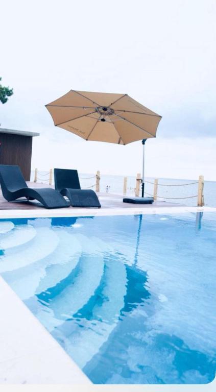 a swimming pool with an umbrella and chairs at Sun Beach Hotel Grigoleti in Grigoleti