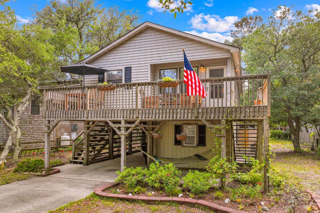 a house with a deck with a flag on it at Sea Swept Cottage OBX in Kill Devil Hills