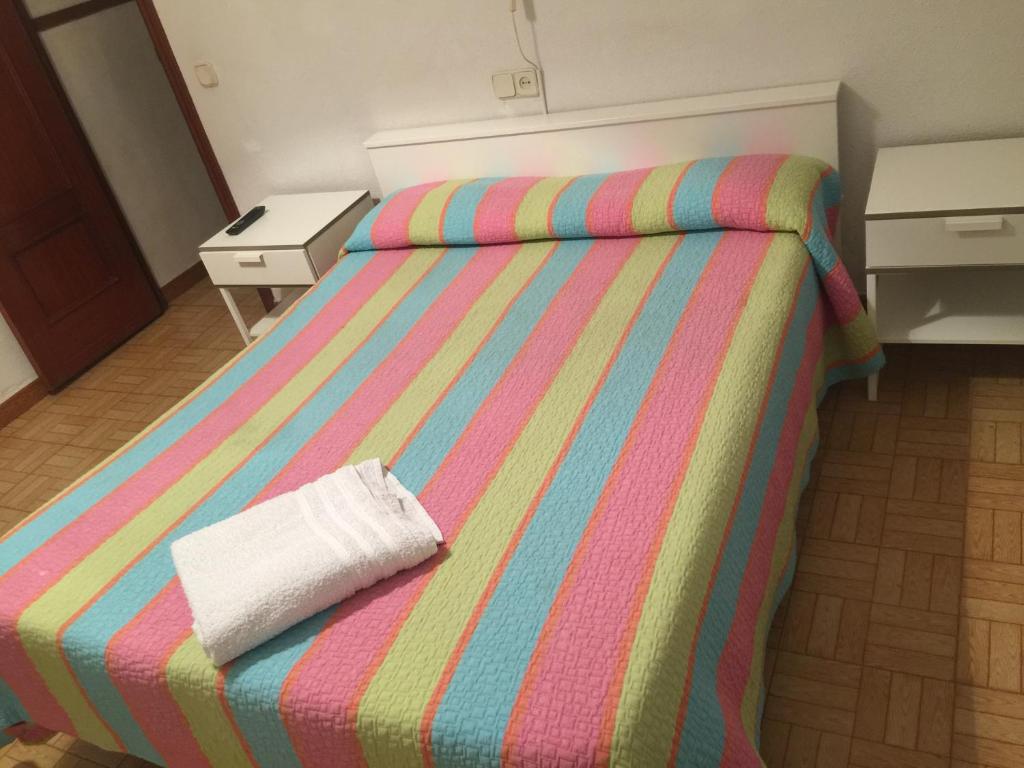 a bedroom with a bed with a striped blanket at Hostal Murcia in Madrid