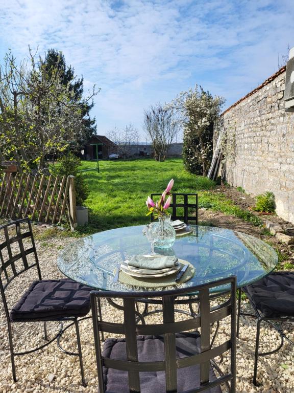 a glass table with chairs and a vase with flowers on it at Mon Cabanon in Tonnerre