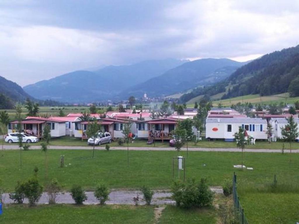 a group of houses in a field with mountains in the background at Victoria Camping Bella Austria in Peterdorf