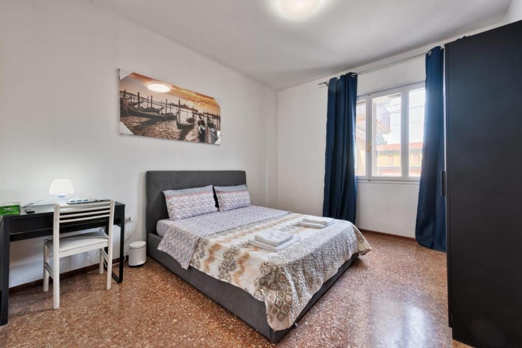 a bedroom with a bed and a desk and a window at Cozy Best Appartment in Marghera
