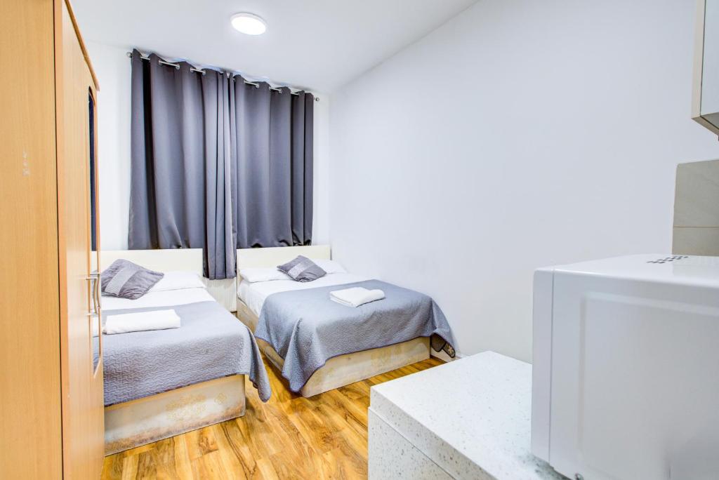 a room with two beds and a television at London Brompton Residence Hotel in London