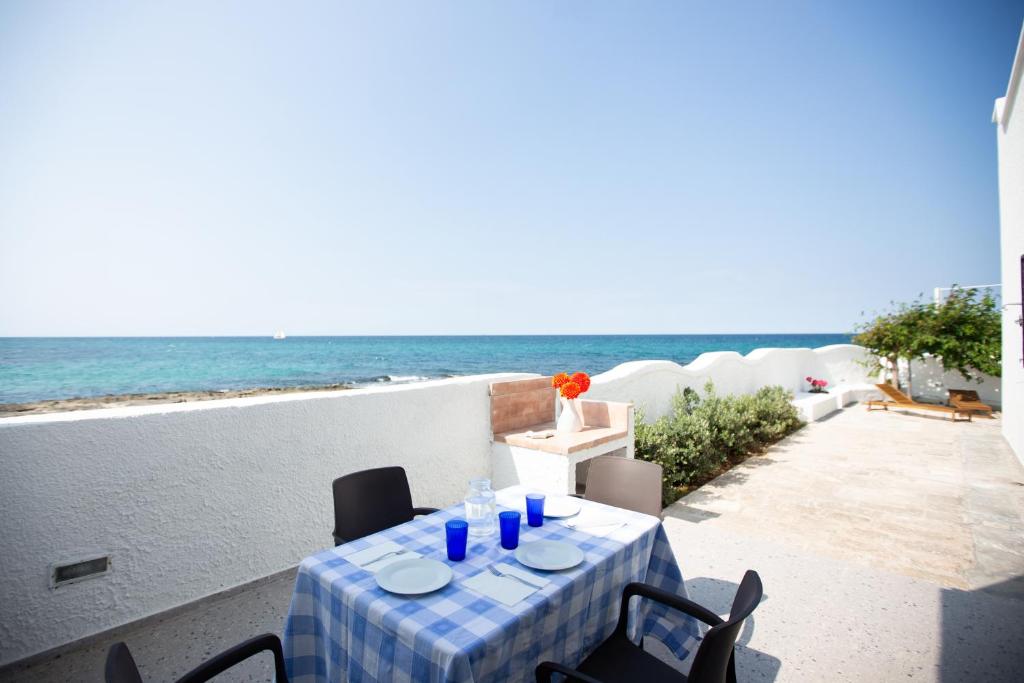 a table on a balcony with the ocean in the background at SeaSide Paradise - Seafront Terrace Apartment by BariHouses in Cozze