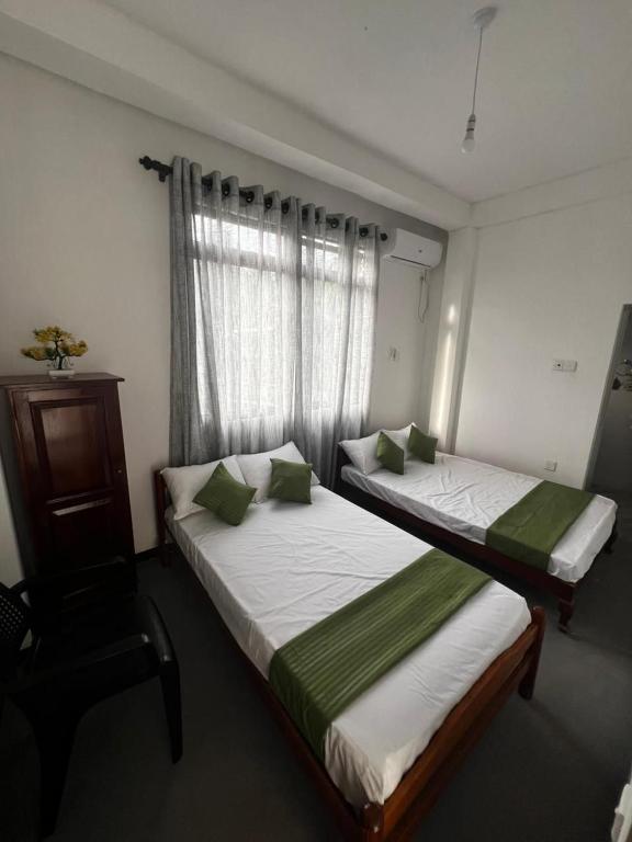 two beds in a room with a window at Kandy Green Nature Villa in Kandy