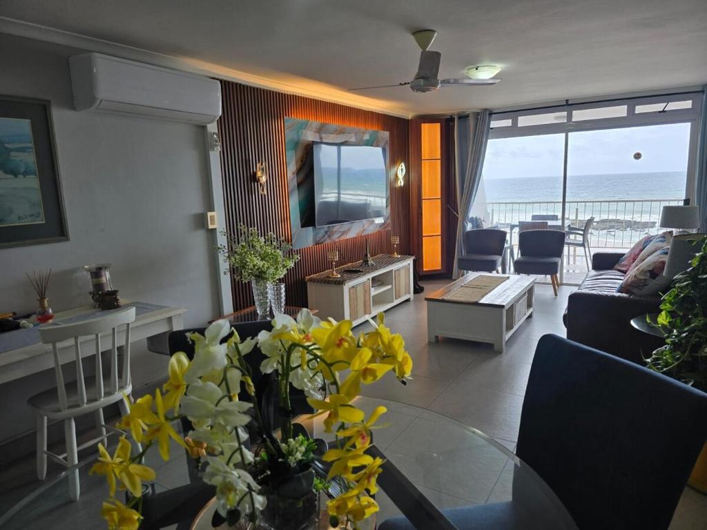 a living room with a couch and a table with yellow flowers at Flat 108 Cozumel, Umdloti Beach Front in Umdloti