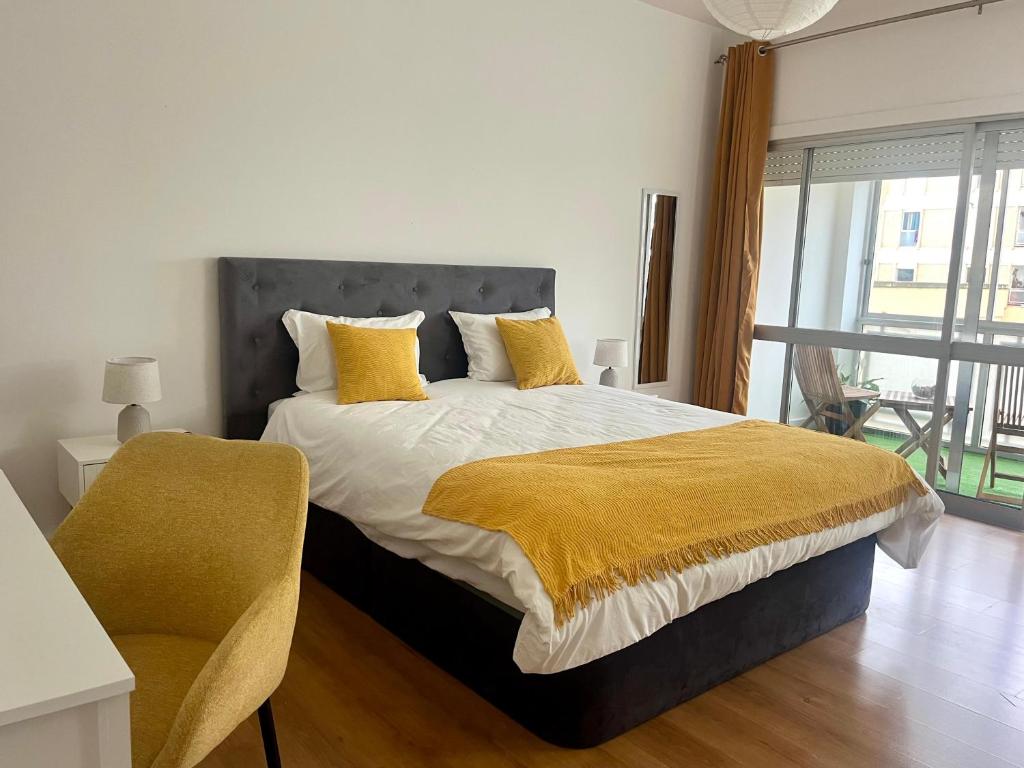 a bedroom with a bed with yellow pillows and a chair at Martins' Happy Home in Coimbra