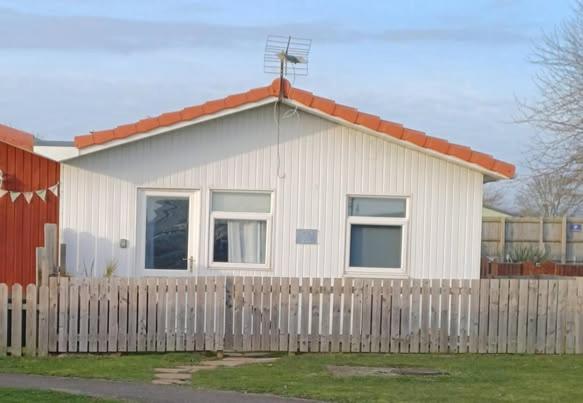 a small white house behind a wooden fence at Sandcastle Chalet in Bridlington